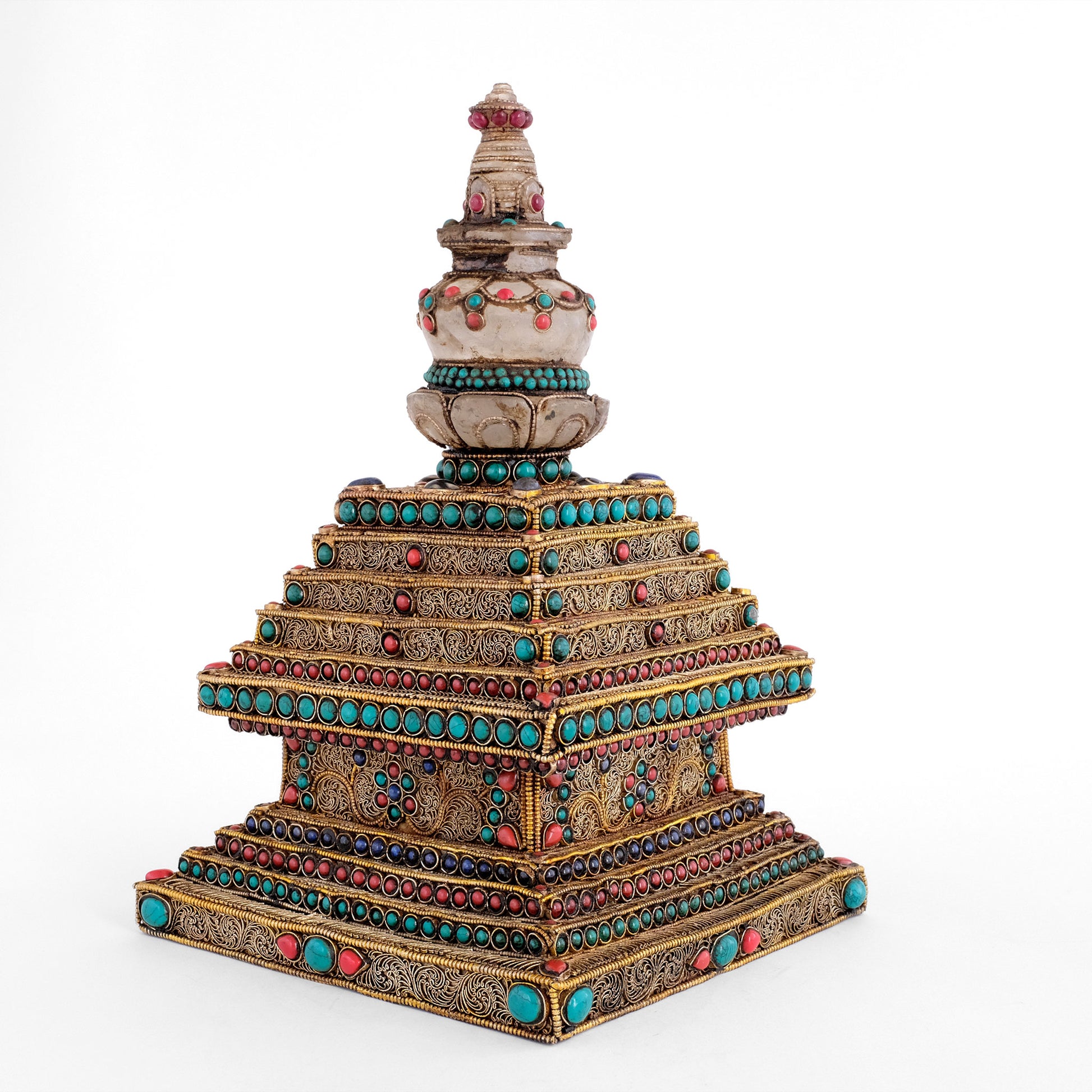 Stupa oder Chorten-Skulptur von einer Ecke aus gesehen. Die Stufen sind mit vergoldetem Perldraht umrahmt. Im Inneren dieses Rahmen sind feine Filigran-Spiralen angeordneten. Für den buddhistischen Hausaltar und als spirituelle Dekoration.