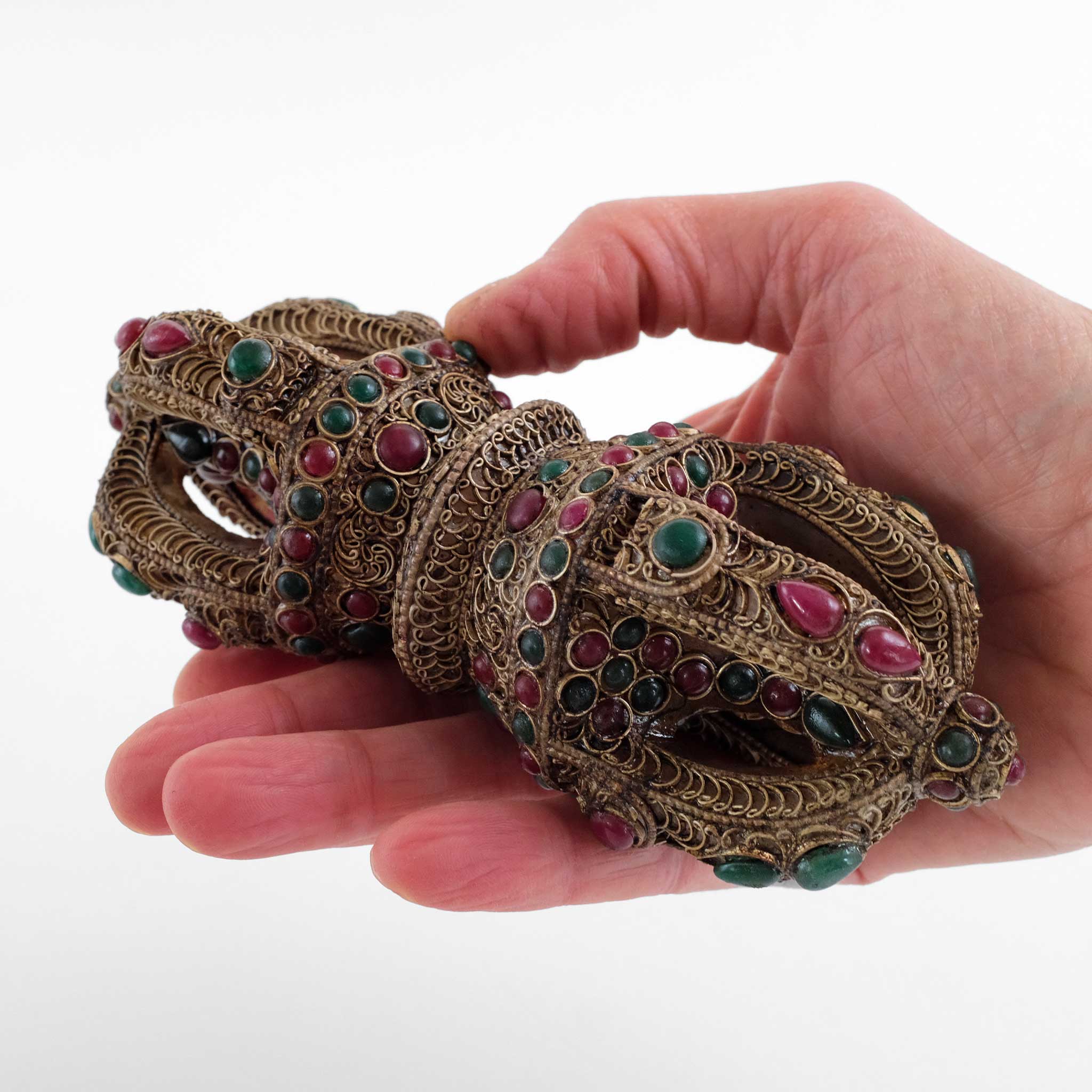 Kristall vajra mit versilbertem Filigran und farbigen Steinen von einer Hand gehalten, als Größenreferenz.