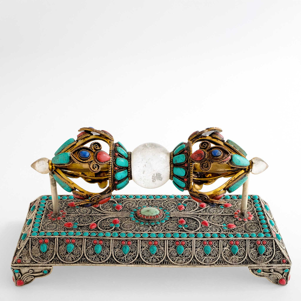 Vajra, auch Dorje genannt, mit Sockel. Der Vajra aus Kupfer, verziert mit Filigran, vergoldet, kombiniert mit Kristall und mit farbigen Steinen besetzt. Der Sockel mit feiner Filigranarbeit in Blumenornamentik, versilbert und ebenfalls mit farbigen Steinen besetzt.