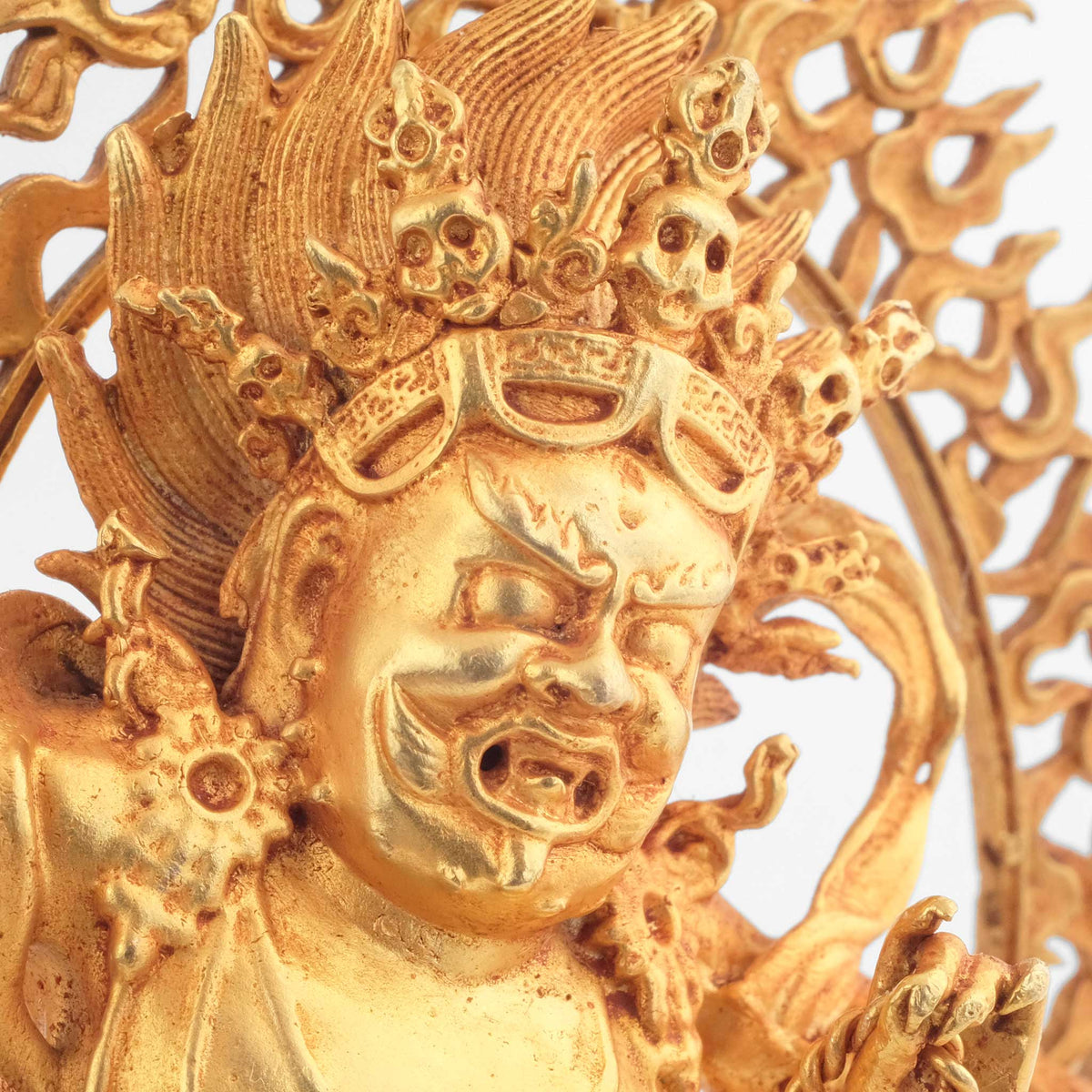 Vajrapani Statue, kleine vergoldete Figur, detaillierter Kupferguss. Detailaufnahme von Gesicht und Totenschädelkrone.