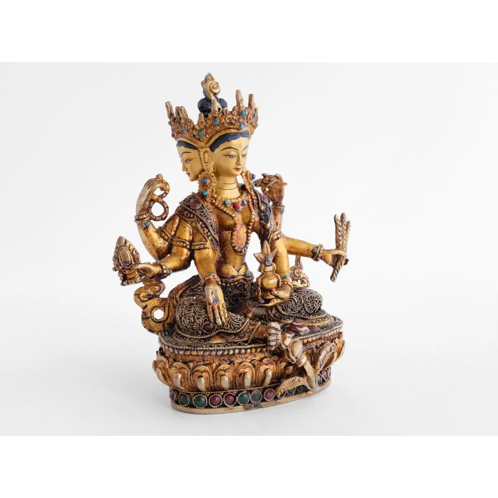 Vasudhara Devi, Göttin mit drei Gesichtern und 6 Armen. Die oberen Hände halten einen Rosenkranz und das Buch der Weisheit, Prajnaparamita. Ihr rechter Fuß ruht auf einer kleinen Vase. Ihre Robe ist verziert mit feinen Filigran Ornamenten.