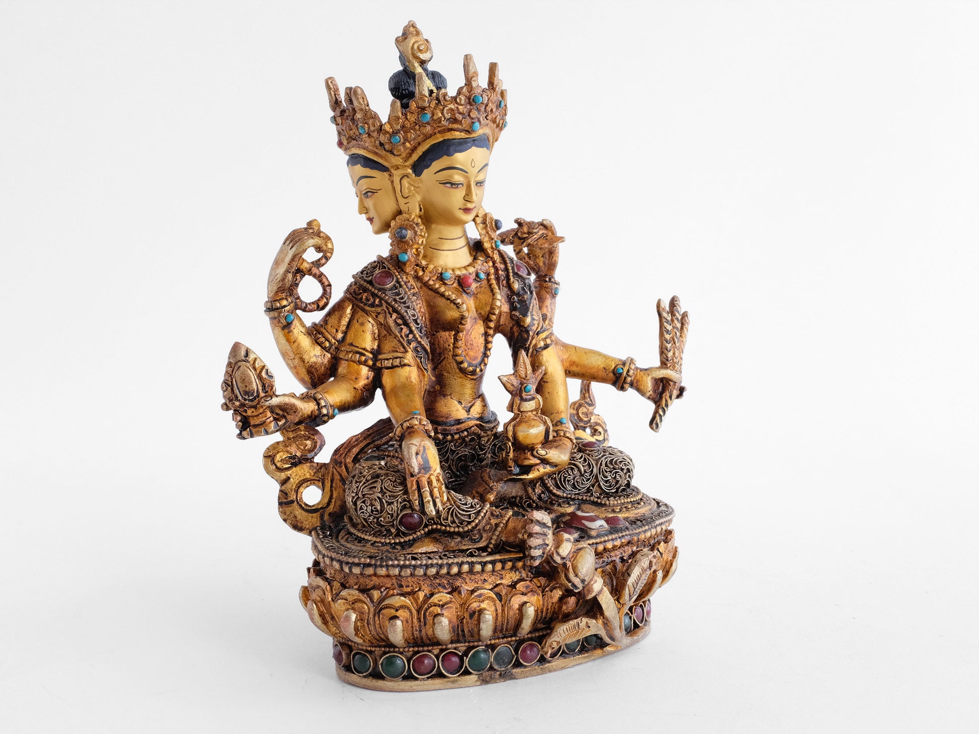 Vasudhara Devi, Göttin mit drei Gesichtern und 6 Armen. Die oberen Hände halten einen Rosenkranz und das Buch der Weisheit, Prajnaparamita. Ihr rechter Fuß ruht auf einer kleinen Vase. Ihre Robe ist verziert mit feinen Filigran Ornamenten.