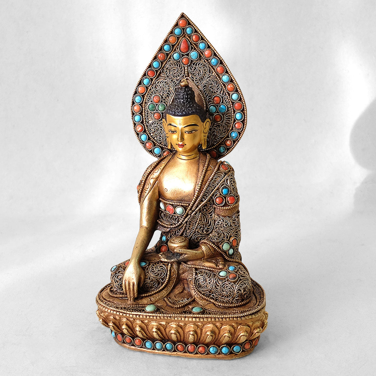 Shakyamuni Figur, aus Kupfer gegossen, mit feinem Filigran verziert, vergoldet und versilbert, mit Türkis und Koralle besetzt. Das Gesicht ist in Gold gefasst.