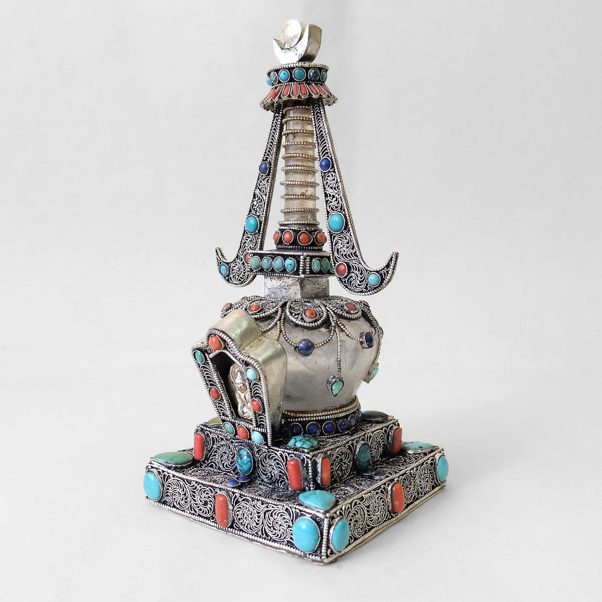 Kleine Stupa aus Kristall und Kupfer. Mit Filigran verziert. Versilbert. Mit Koralle, Lapislazuli und Türkis besetzt.