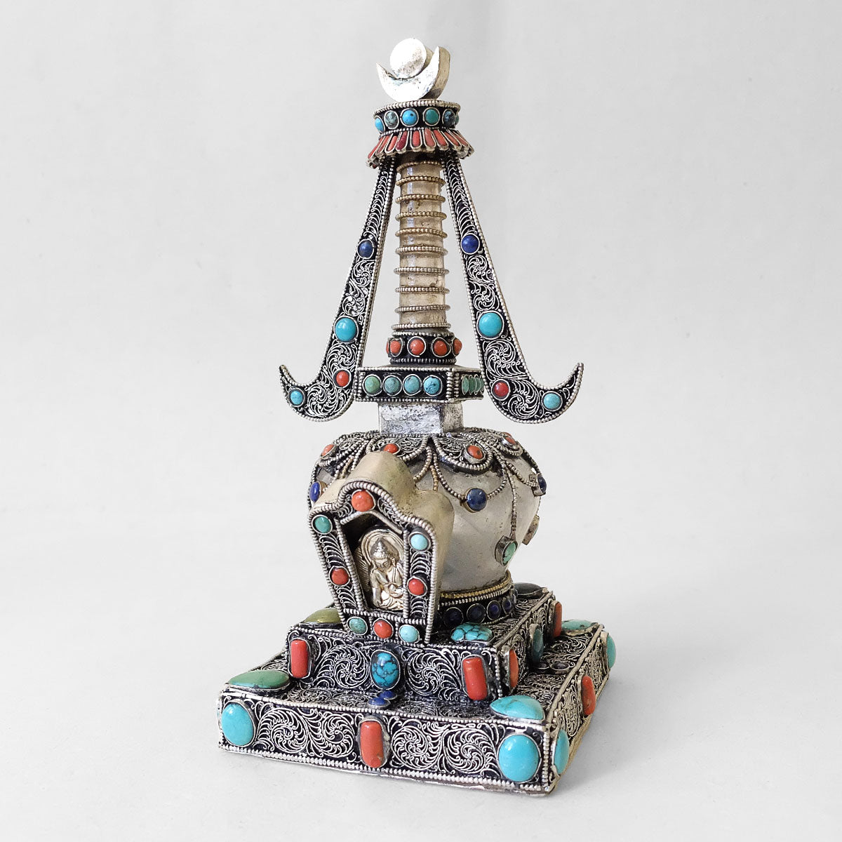 Kleine Stupa aus Kristall und Kupfer. Mit Filigran verziert. Versilbert. Mit Koralle, Lapislazuli und Türkis besetzt.