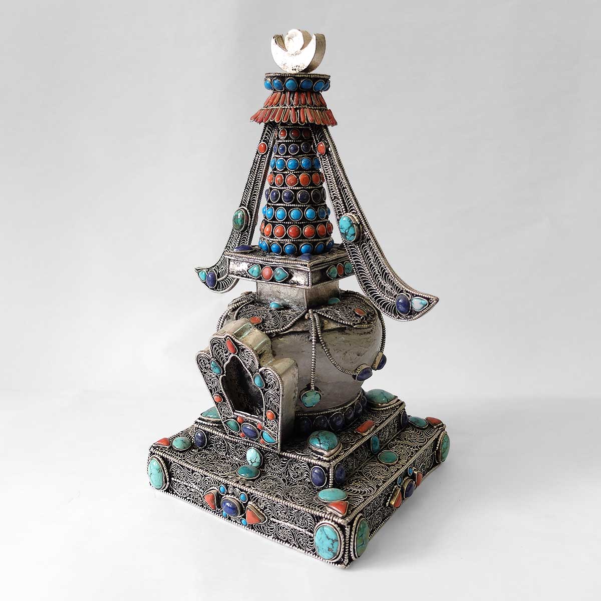 Stupa aus Kupfer, mit Filigran verziert, versilbert, mit Türkis, Koralle und Lapislazuli besetzt. Die Kuppel ist aus Kristall. 