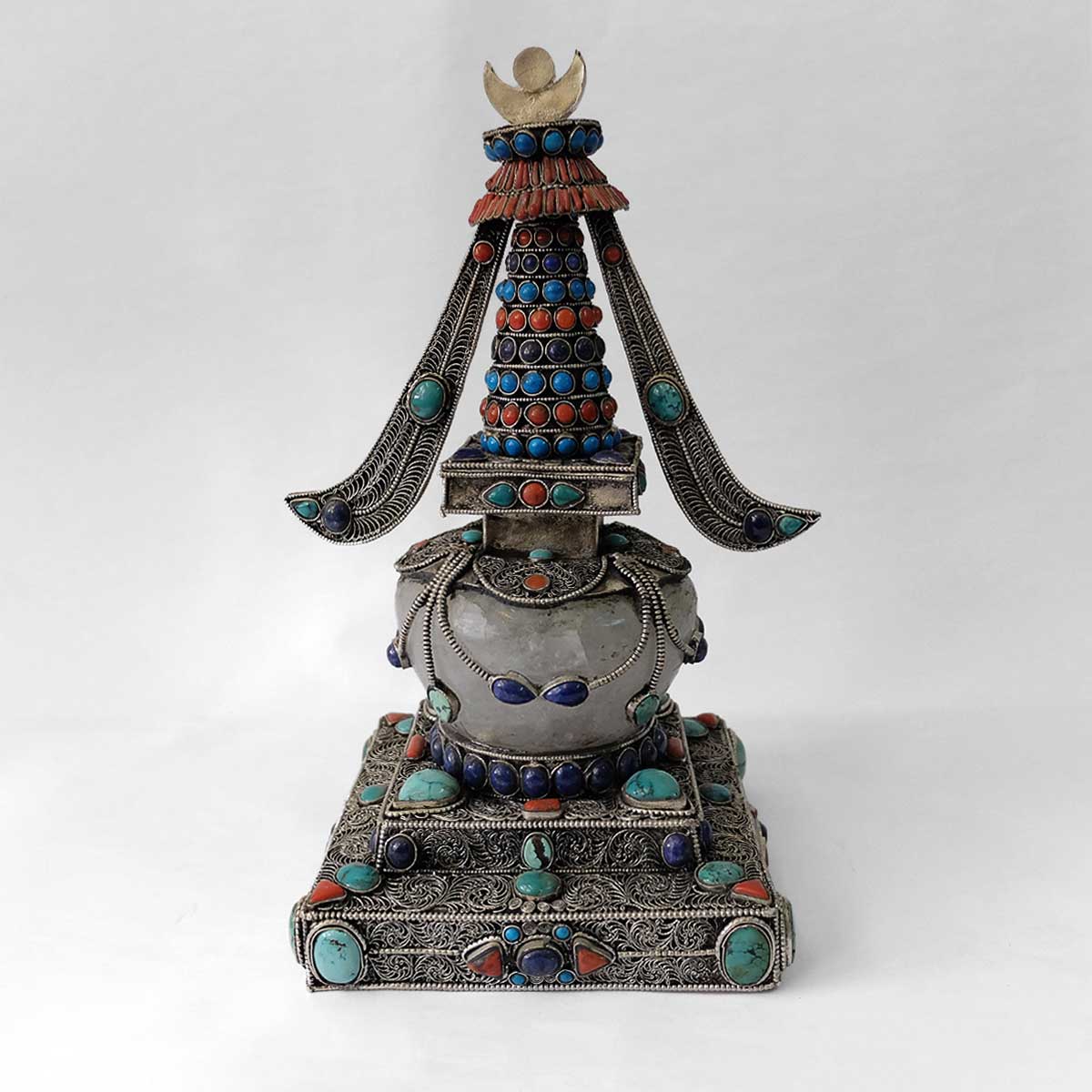 Stupa aus Kupfer, mit Filigran verziert, versilbert, mit Türkis, Koralle und Lapislazuli besetzt. Die Kuppel ist aus Kristall. 